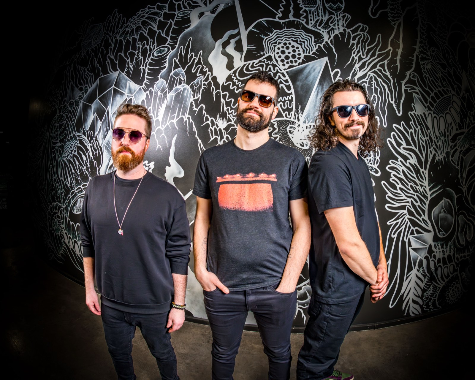 The three members of lespecial — Luke Bemand, Jonathan Grusauskas and Rory Dolan — in front of a black-and-white line-drawn mural